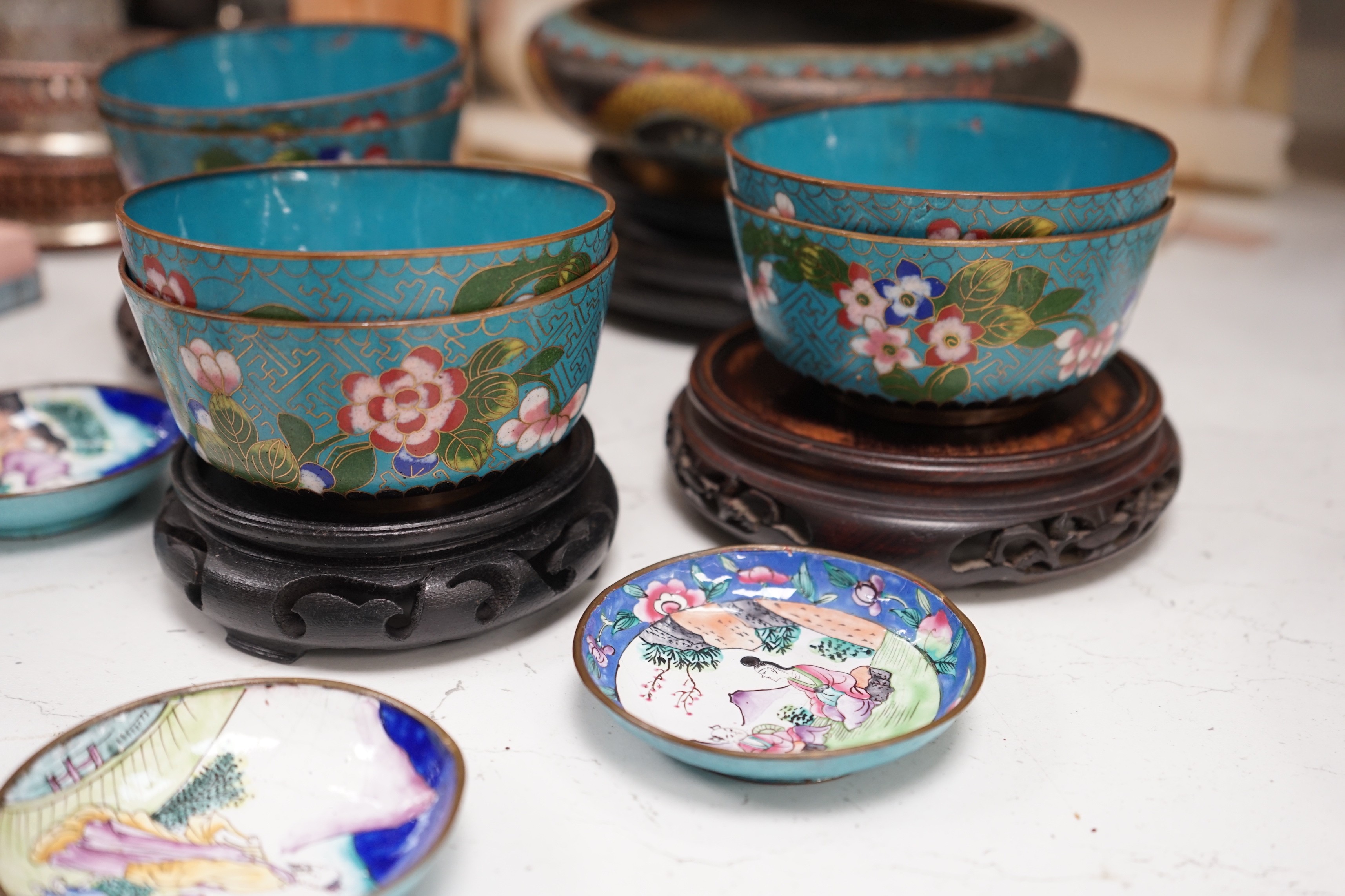 A Chinese cloisonné enamel 'dragon' bowl, six Chinese floral cloisonné enamel bowls and four Canton enamel dishes and wood stands